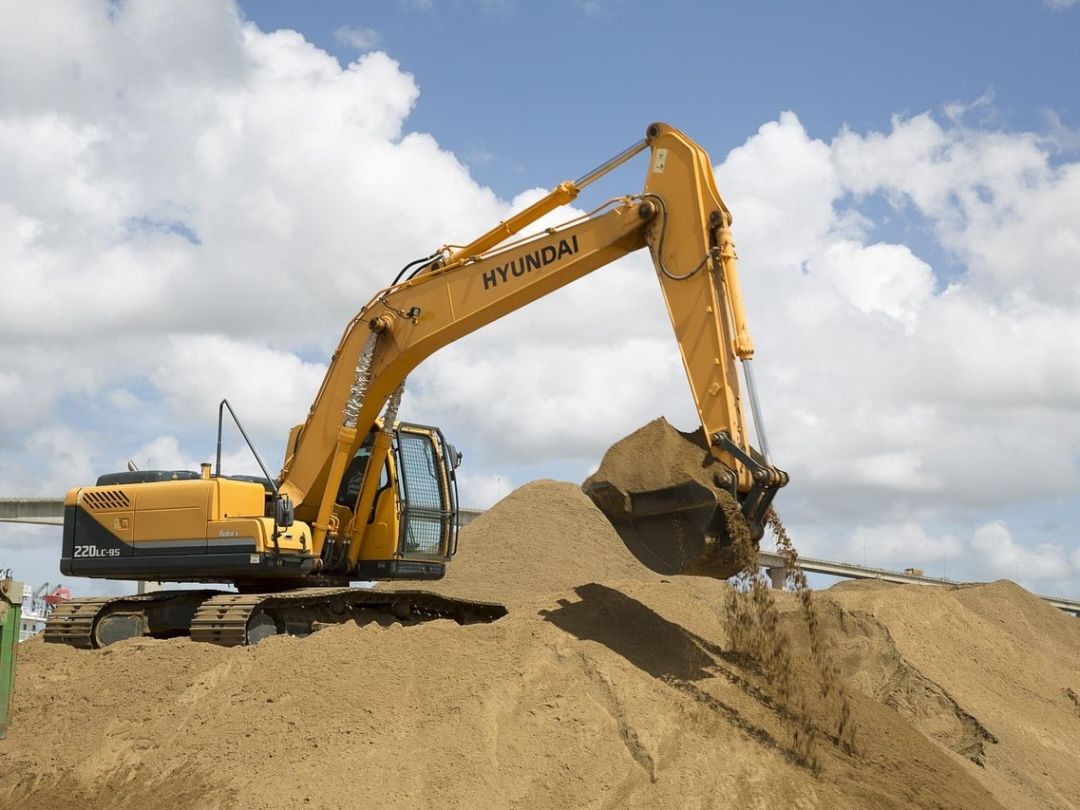 Bagger auf einer Baustelle, der Erdreich für die Baugrube eines Neubaus bewegt