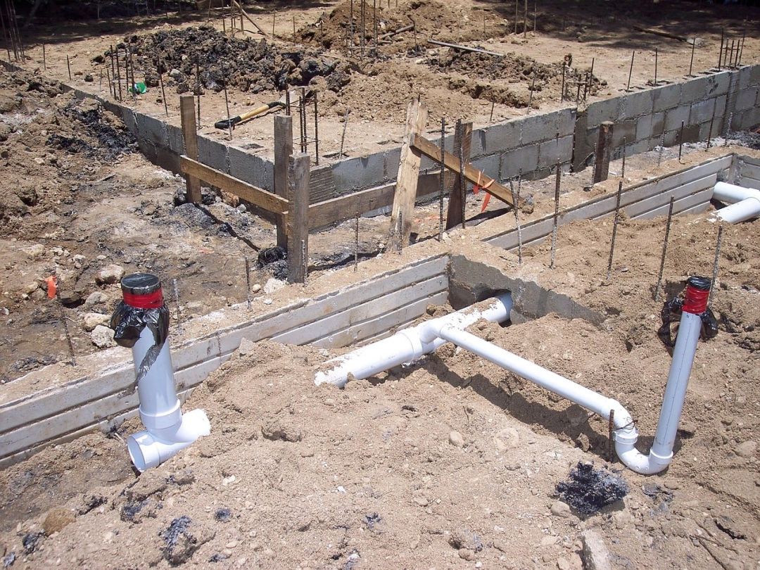 Streifenfundamente aus Beton mit Schalung und bereits verlegten Leitungen vor dem Weiterbau