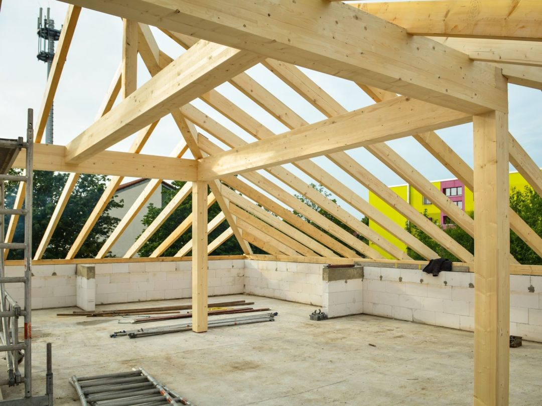 Neuer Dachstuhl aus Holz mit Sparren und Pfetten auf den fertigen Mauerkronen eines Neubaus
